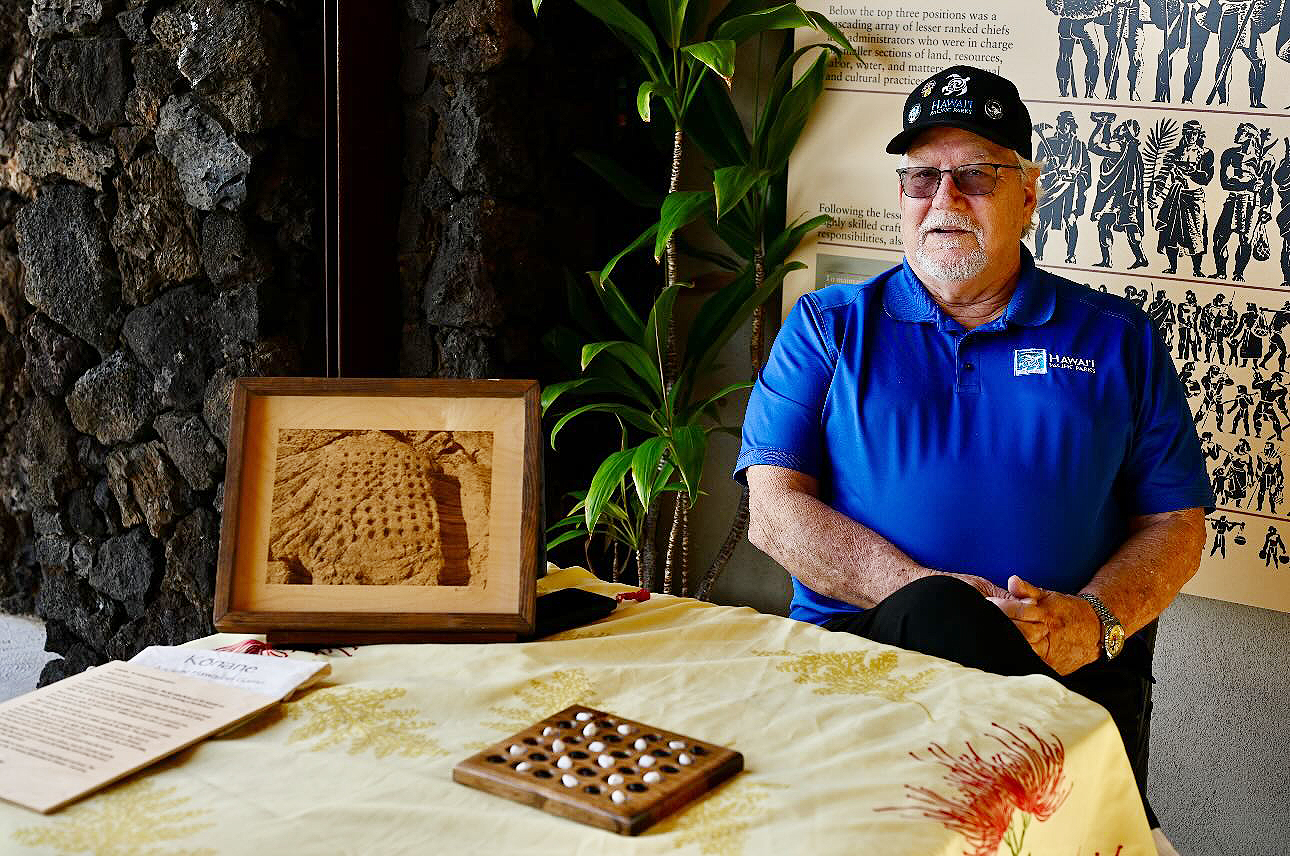 Ed Dowling sits at a table with a kōnane board in front of him at PUHE.